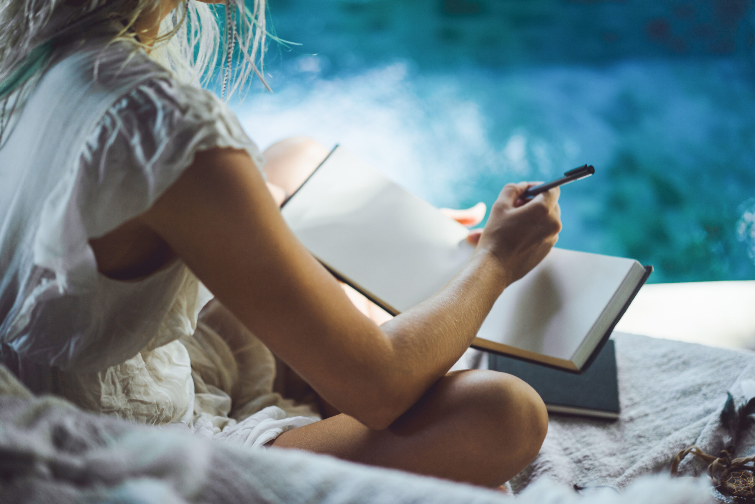 Chica escribiendo en un cuaderno desde casa, representando el proceso creativo y la redacción profesional en el ghostwriting.