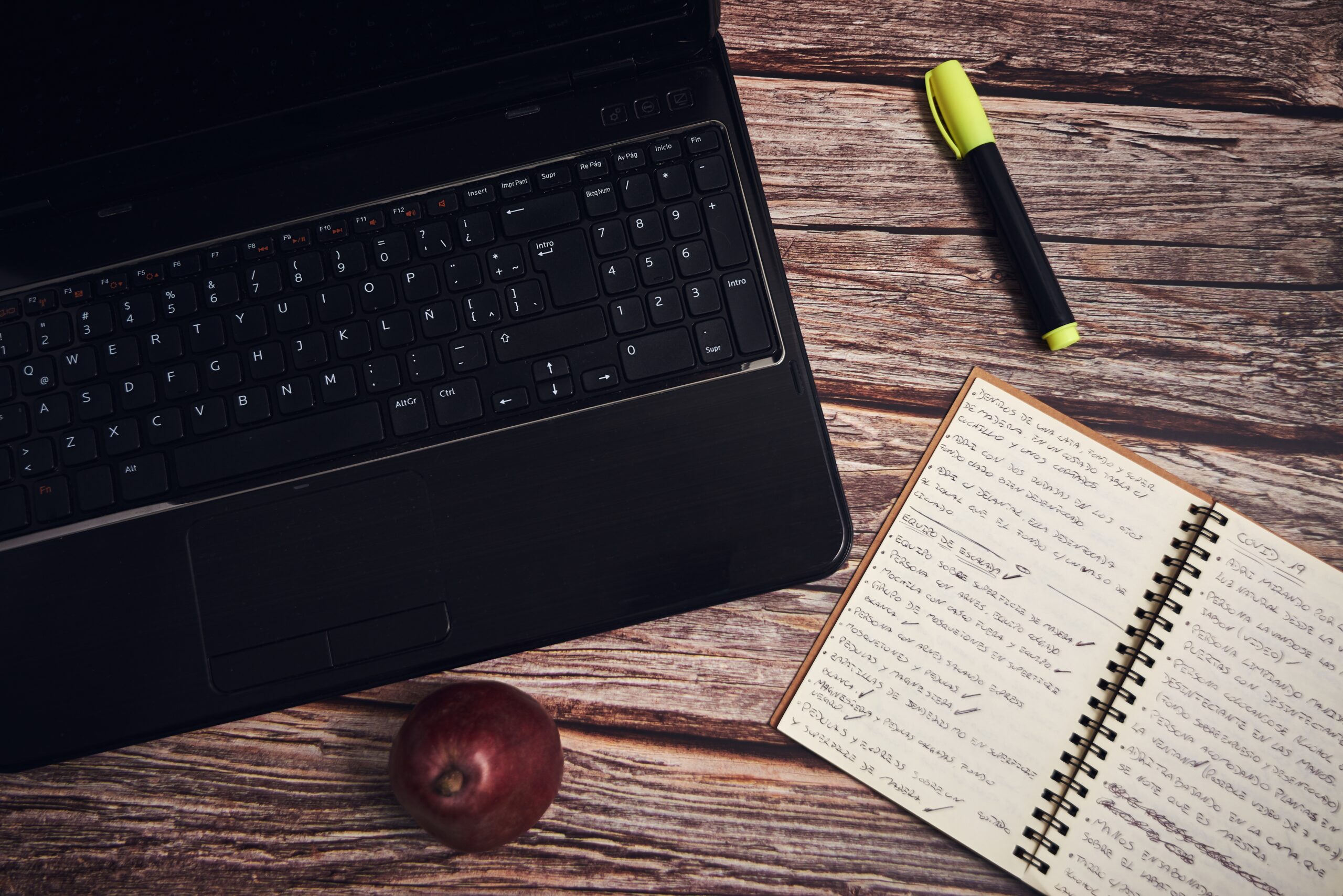 Portátil y cuaderno sobre un escritorio de madera, representando el proceso de planificación y redacción en el ghostwriting.
