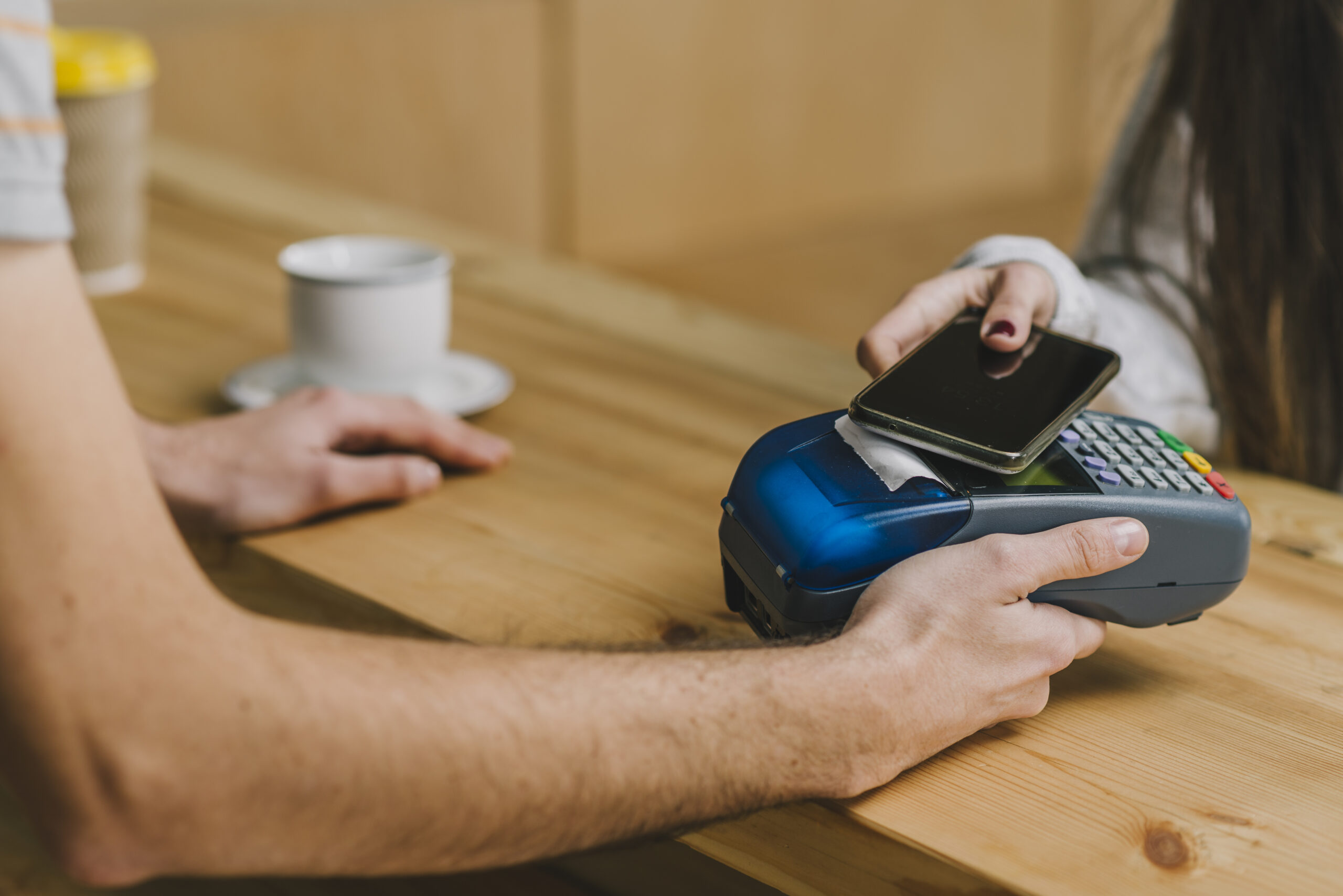 Barista aceptando un pago con tarjeta de crédito o móvil en un sistema de pago digital.