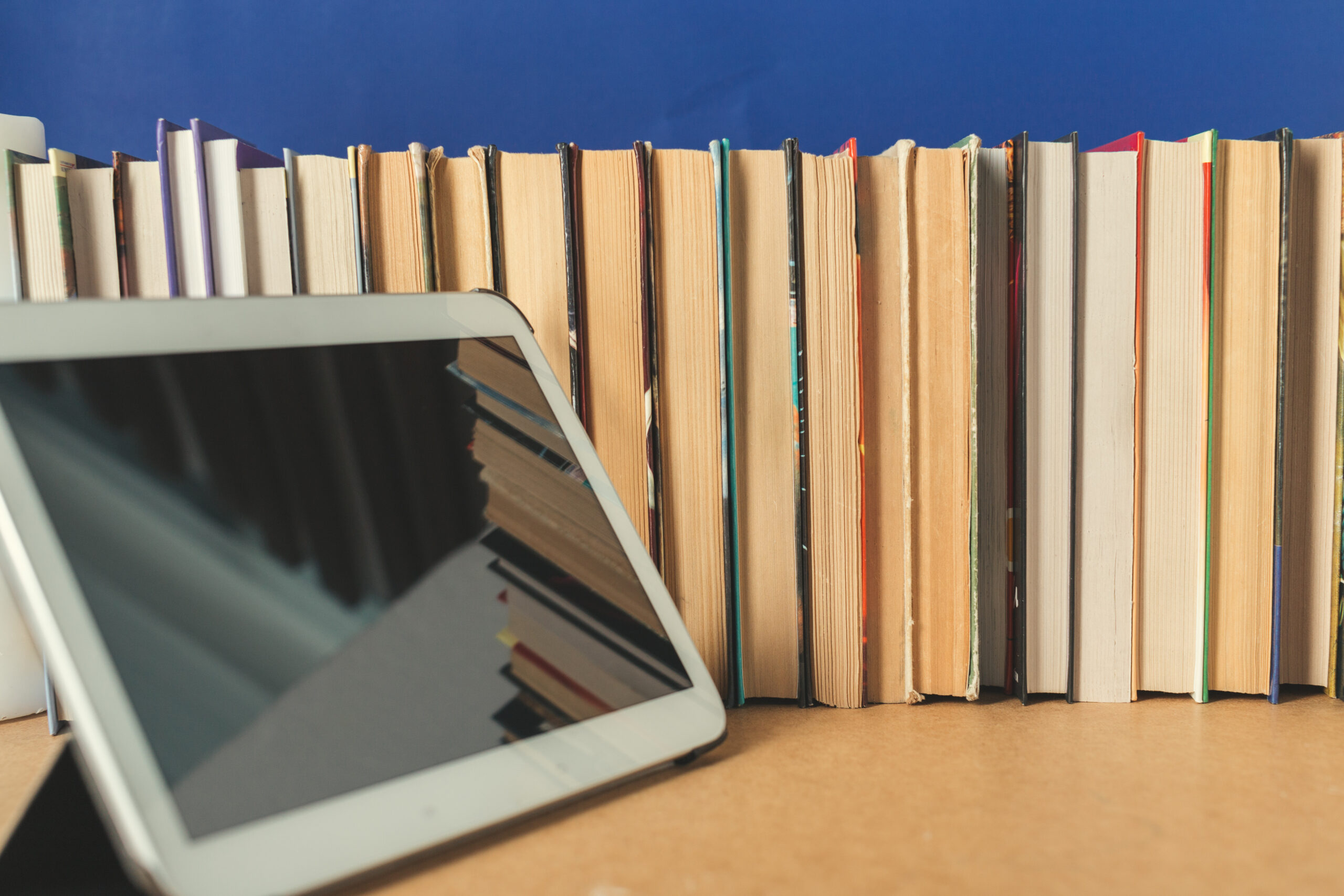Libros y dispositivo de lectura que representan la creación y el consumo de ebooks y contenido digital.