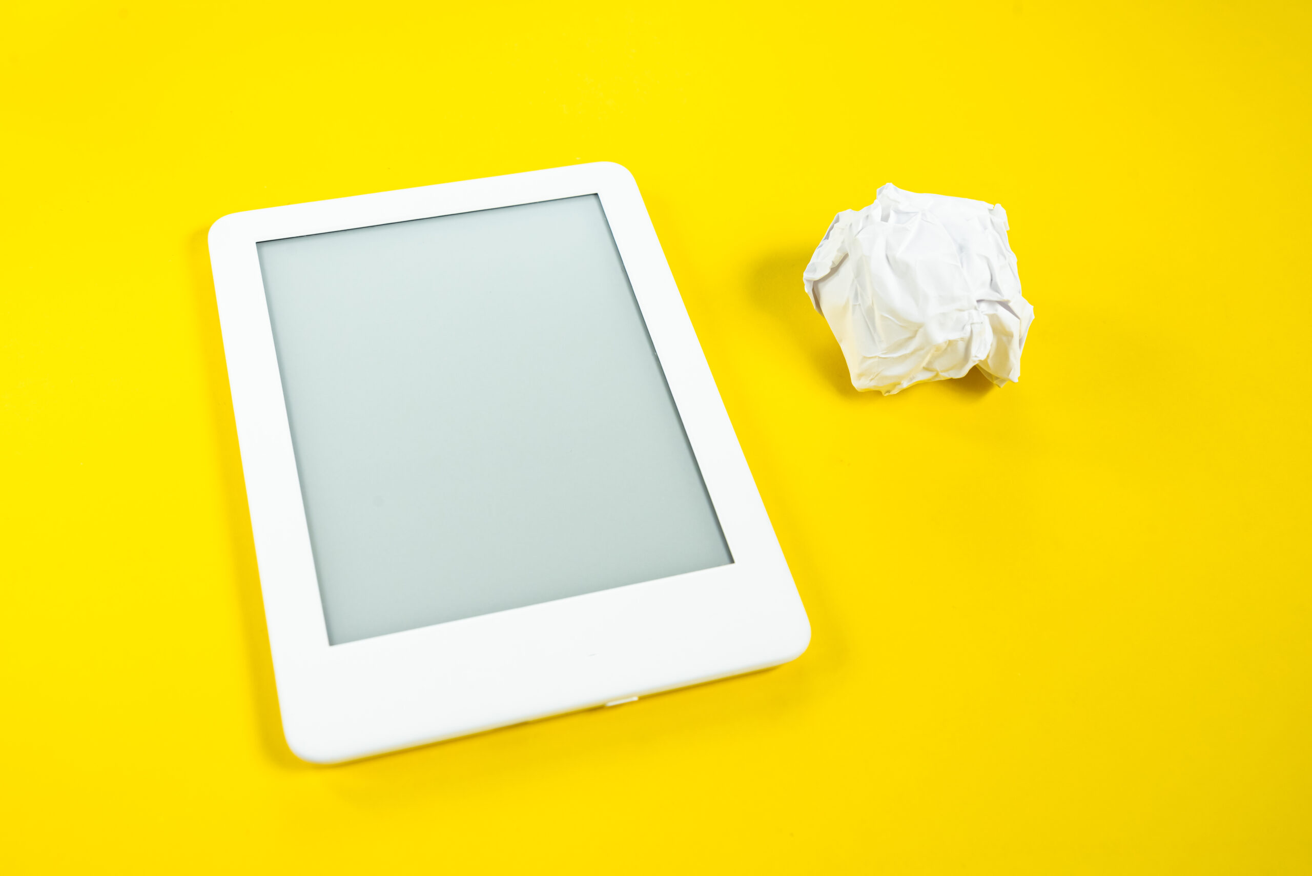 Lector de ebooks sobre fondo amarillo con elementos que representan el proceso de revisión y mejora de contenido digital.