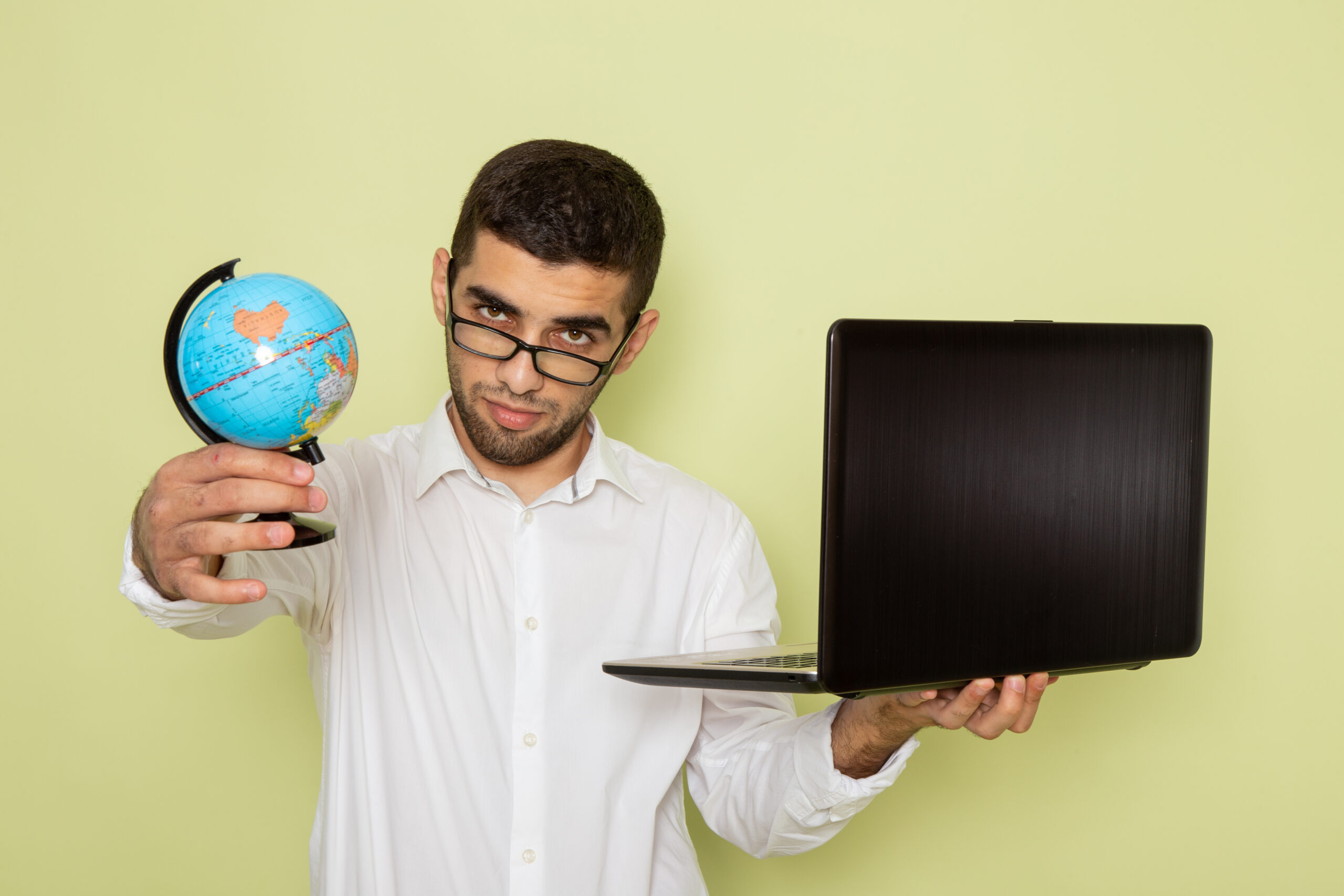 Trabajador de oficina sosteniendo portátil y globo terráqueo, relacionado con globalización y negocios digitales.