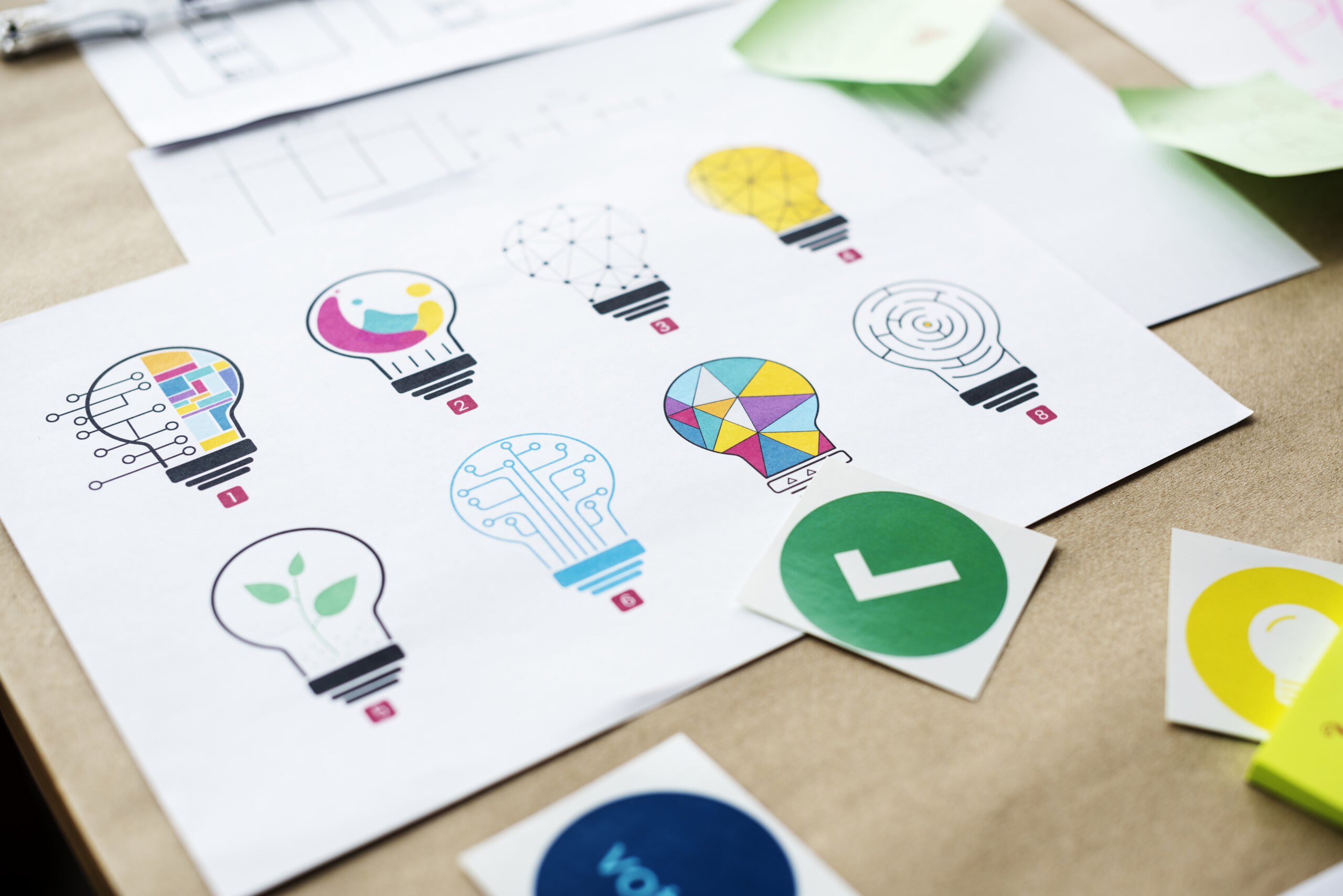 Bombillas de papel junto a un símbolo de verificación que representan la coherencia y la consistencia en una estrategia de branding.