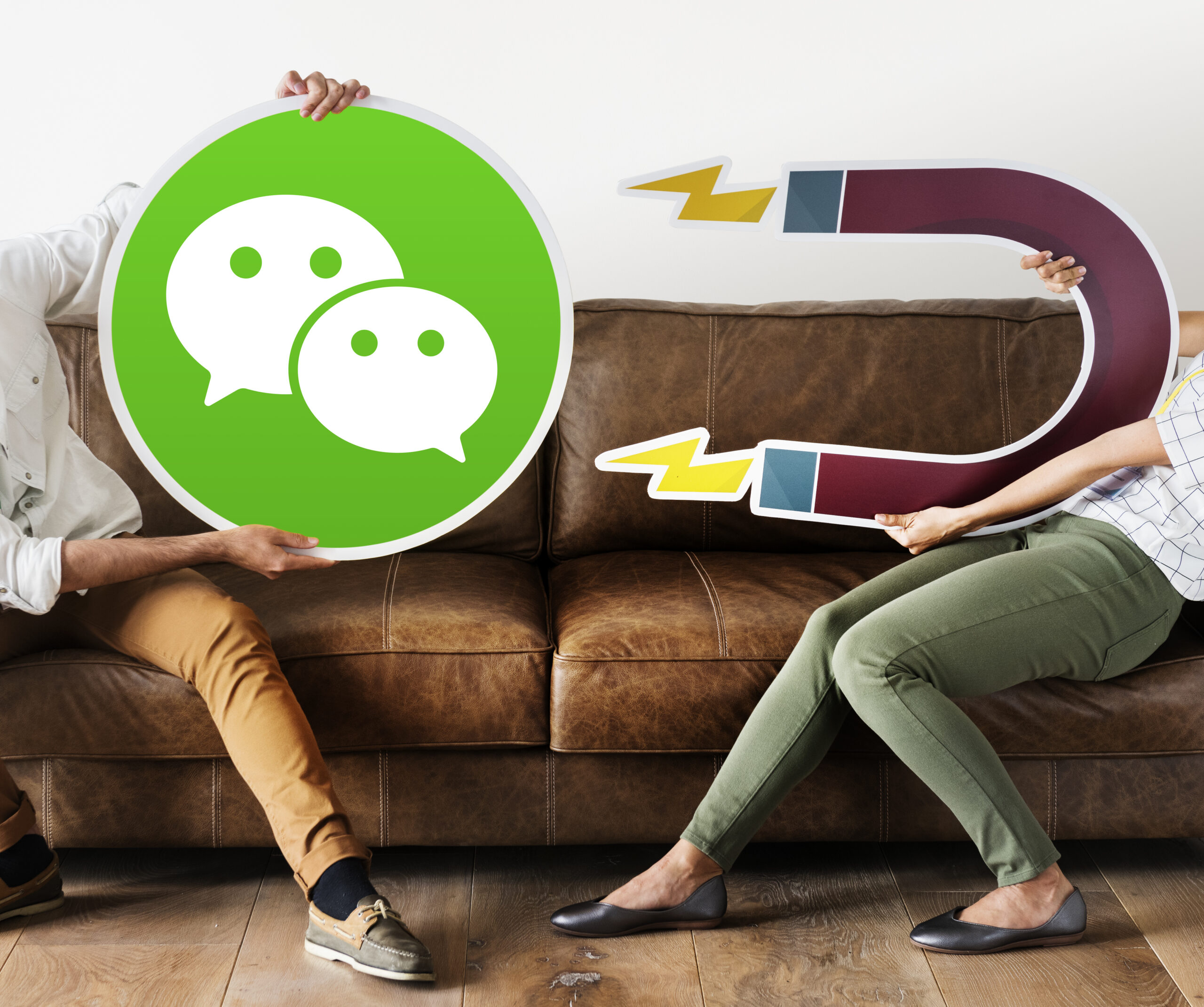 Personas sosteniendo el icono de WeChat, representando la comunicación digital y las redes sociales.