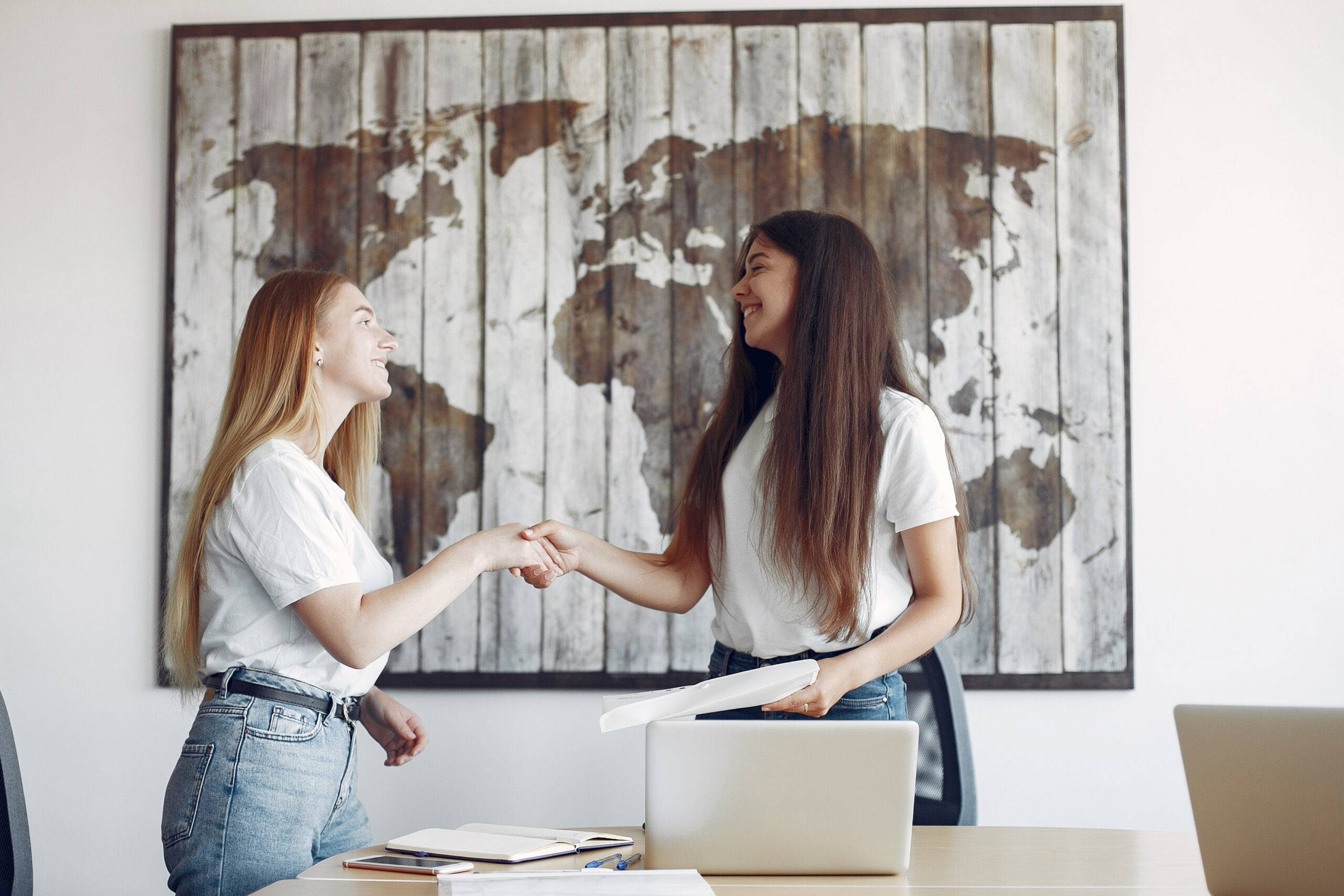 Dos mujeres trabajando en oficina en equipo, relacionadas con proyectos digitales y colaboración global.