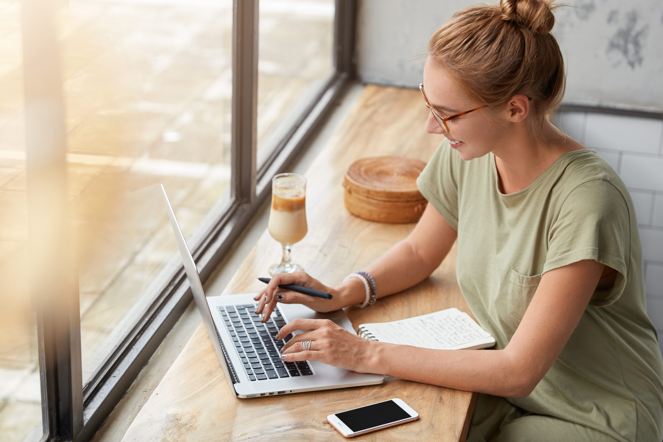 Mujer freelancer trabajando en copywriting y marketing digital desde una cafetería con portátil.
