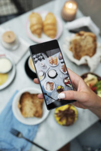 Carta digital de restaurante en smartphone junto a platos de comida, mostrando una experiencia gastronómica moderna.