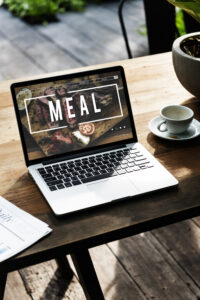 Página web profesional para restaurante mostrada en ordenador portátil y smartphone con diseño moderno, carta digital y sistema de reservas online.